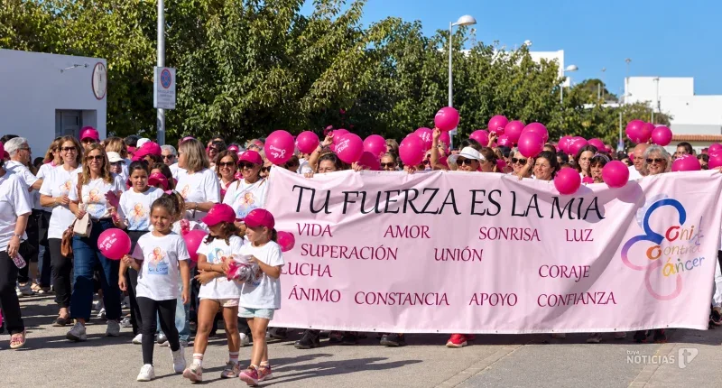 La marcha solidaria con Conil Contra el Cáncer llenó las calles de la localidad tras esta pancarta.